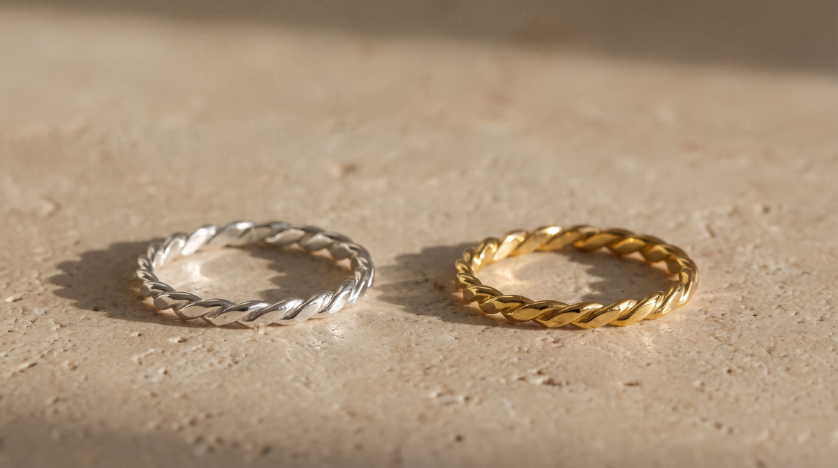 The same twisted rope ring in sterling silver and gold vermeil side by side on warm stone
